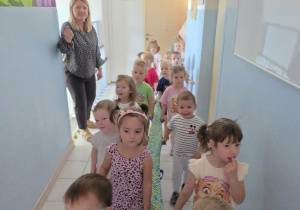 Dzieci idą korytarzem przedszkola i poznają jego zakamarki.