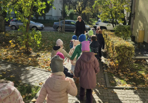 Dzieci spacerują osiedlowymi alejkami w okolicy przedszkola.