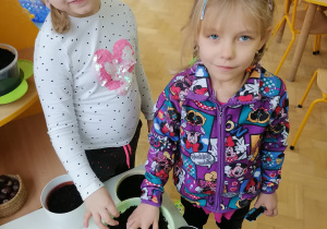 Natalka i Danusia uśmiechnięte dokańczają sadzenie fasoli.