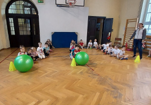 Dzieci przygotowują się do rywalizacji. Ich zadaniem było toczenie wielkiej, zielonej piłki.