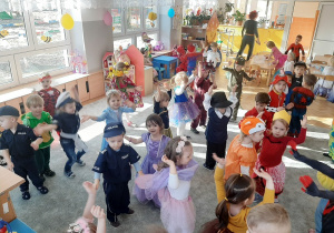 Dzieci ustawione w rozsypce bawią się i tańczą.