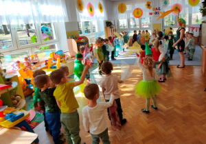 Dzieci tańczą przy muzyce, machając rytmicznie chusteczkami trzymanymi w dłoni.