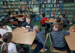 Dzieci siedzą w czytelni biblioteki.