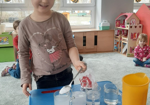 Nikola dodaje soli do szklanki z wodą.