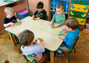 Dzieci siedzą przy stoliku- uczą się prawidłowego szczotkowania zębów