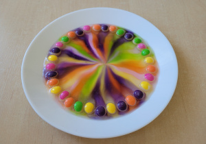 Tęcza na talerzu powstała z połączenia kolorowych cukierków i wody.
