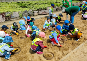 Dzieci bawią się w paleontologów- prowadzą prace wykopaliskowe.