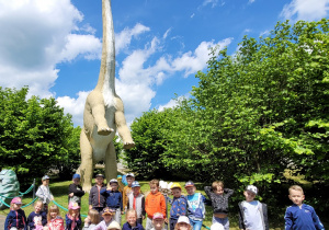 Dzieci stoją przed dinozaurem.
