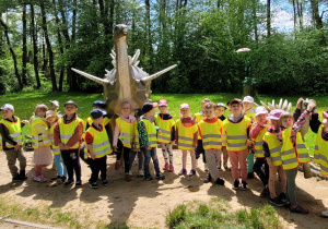 Dzieci stoją przed dinozaurami.