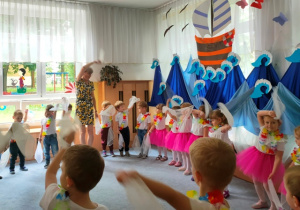 Dzieci prezentują taniec z chusteczkami- machają nimi nad głową.