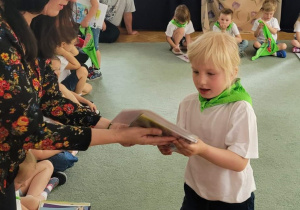 Dziewczynka otrzymuje od nauczycielki książkę.