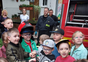 Dzieci próbują utrzymać węża strażackiego.