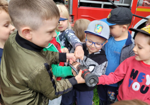 Dzieci trzymają weża strażackiego.