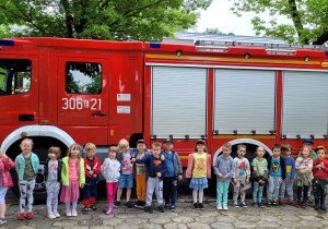 Dzieci stoją przed wozem strażackim.