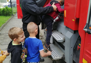 Dzieci zwiedzają wóz strażacki.