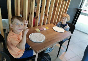 Chłopcy robią pizze według własnego pomysłu.
