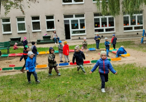 Chłopcy bawią się w ganianego biegając po trawiastej części ogrodu.