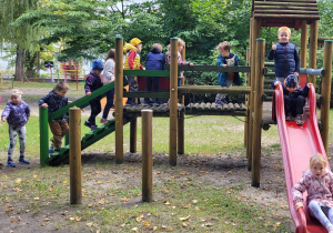Dzieci w ogrodzie przedszkolnym zjeżdżają ze zjeżdżalni.