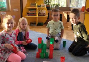 Dzieci w grupie układają wieże z kolorowych kubeczków.