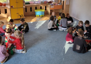 Dzieci pracują w grupach na dywanie.