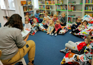 Dzieci słuchają bajkę czytaną przez panią bibliotekarkę.