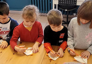 Dzieci wykonują lisa z talerzyków papierowych.