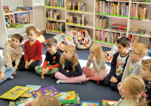 Dzieci siedzą na dywanie i słuchają opowiadania o lisie.