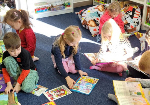 Dzieci przeglądają różne książki w czytelni.