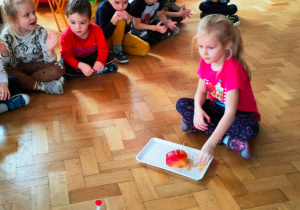 Dziewczynka wbija wykałaczki w połówkę jabłka.