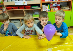 Dzieci obserwują, jak napełnia się balon gazem- wynik reakcji sody z octem.