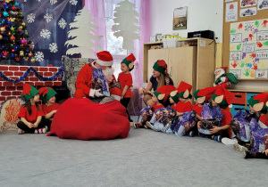 Święty Mikołaj rozdaje prezenty wszystkim dzieciom.