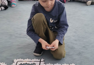 Chłopiec układa puzzle z trasą dla ozobota.