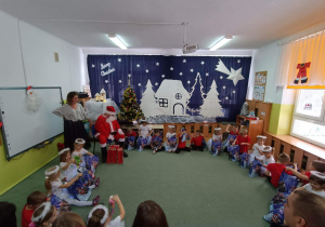 Mikołaj rozdaje prezenty dzieciom.