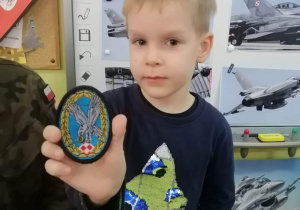 Chłopiec prezentuje naszywkę Polskich Sił Powietrznych.