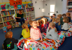 Dzieci w skupieniu słuchają bajki o pingwinie czytanej przez panią Anię.