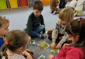 Dzieci w małych grupach układają puzzle związane ze znanymi bajkami.
