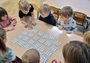 Dzieci grają w memory w małej grupie rówieśniczej.