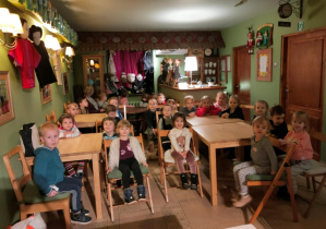 Dzieci siedzą przy stolikach, buziami zwrócone do sceny.