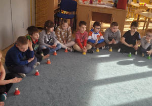 Dzieci siedzą na dywanie grają na dzwonkach.