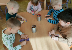 Dzieci pracują przy stolikach- kolorują zakładkę do książki.