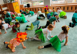 Dzieci przy dźwiękach muzyki poruszają się po dywanie jak żółwie.