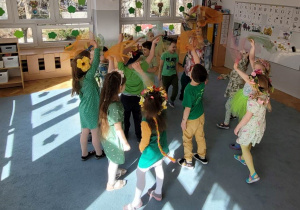 Dzieci z kolorowymi chustkami tańczą w rytm wiosennych piosenek.
