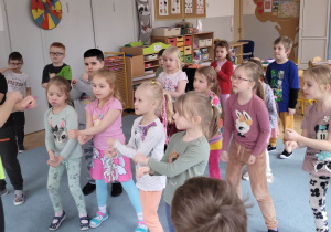 Dzieci naśladują ruchu pokazywane przez intruktorkę tańca.