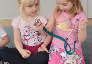 Dziewczynki oglądają stetoskop.