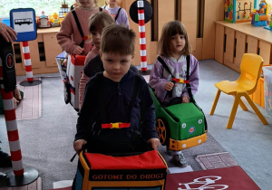 Dzieci zamienione w pojazdy ruchu drogowego przejeżdżają na zielonym świetle.