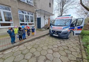 Dzieci zatykają uszy przy syrenie wydawanej przez ambulans.