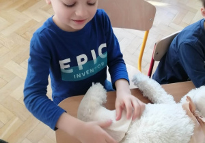 Chłopiec bandażuje misiowi nogę.
