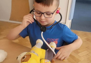 Chłopiec bada maskotkę stetoskopem.
