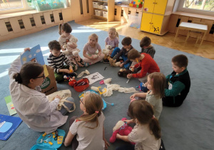 Dzieci siedzą na dywanie i słuchają o zdrowiu.