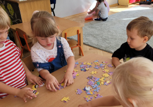 Dzieci układają wspólnie puzzle.